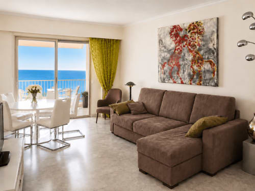 Spacieux salon avec vue sur mer dans un appartement de Cannes, canapé lit marron, salle à manger moderne et balcon avec vue