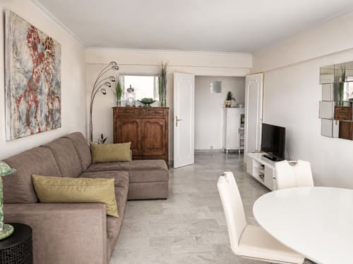 Appartement moderne avec vue mer à Cannes, canapé marron mobilier en bois, TV 
écran plat et séjour ouvert