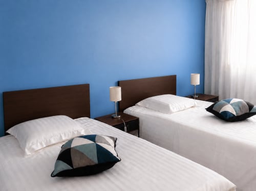 Chambre double moderne de l'appartement Le Fettolina à Cannes avec murs bleus, têtes de lit en bois foncé et literie blanche