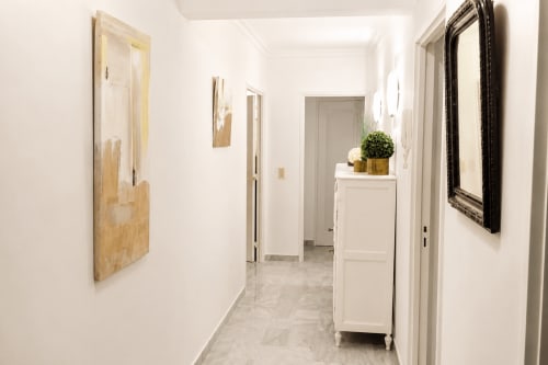 Couloir lumineux d'un appartement à Cannes avec murs blancs, miroirs aux cadres bois et noirs, plantes en pots et portes de chambres