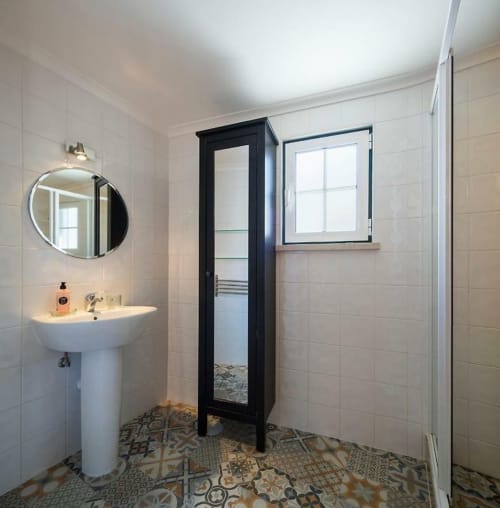 Modern bathroom with pedestal sink, circular mirror, and black-framed standing mirror in Orchard View Villa at Quinta Boa