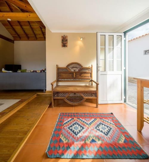 Wooden bench with decorative backrest in Orchard View Villa at Quinta Boa Vida, Alcobaça, with colorful kilim rug and garden