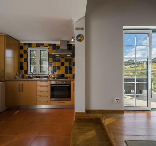 Modern kitchen with wooden cabinets and checkerboard backtile at Quinta Boa Vida, Alcobaça, with garden views through patio