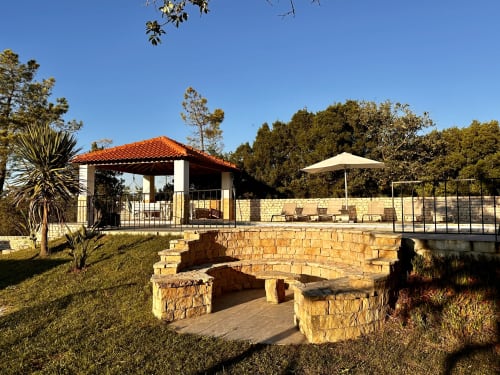 Stone fire pit with seating area at Quinta Boa Vida in Alcobaça, Portugal, with villa and garden views