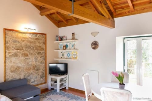 Modern living room at Quinta Boa Vida villa in Alcobaça with wooden beams, TV, shelving, and garden view doors