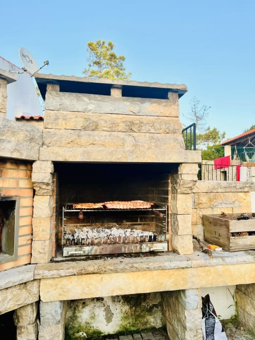 Traditional stone barbecue with roasting meat at Quinta Boa Vida mountain chalet in Alcobaça, Portugal
