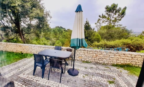 Outdoor patio at Quinta Boa Vida in Alcobaça with dining table, blue umbrella, and mountain views