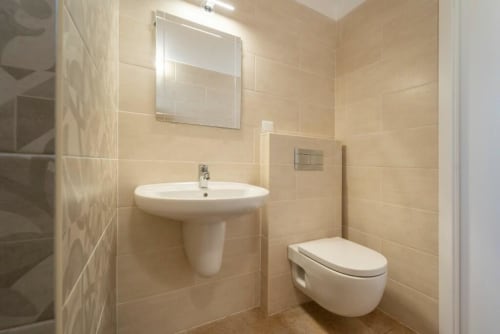 Modern bathroom at Quinta Boa Vida Mountain View Chalet in Alcobaça with pedestal sink, wall-mounted toilet, and beige tile