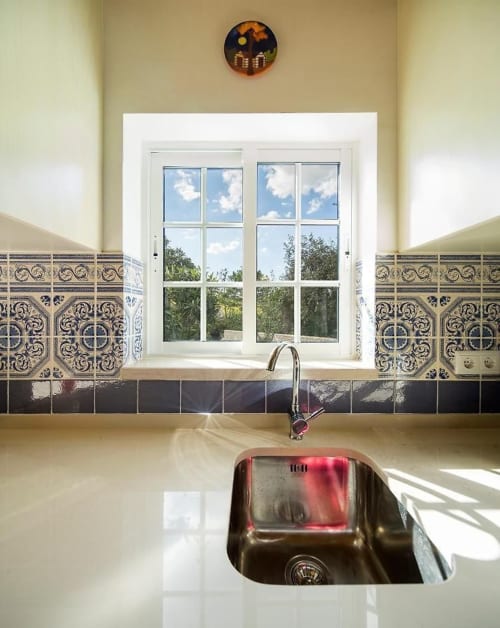 Modern kitchen sink with stainless steel basin and decorative tile backsplash, window overlooking Alcobaça landscape at