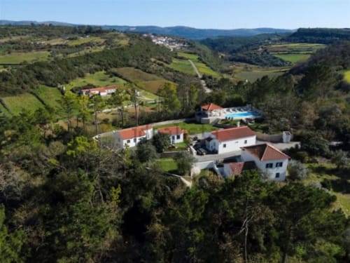 Aerial view of Quinta Boa Vida cottage with pool nestled in lush green valleys of Alcobaça, Portugal