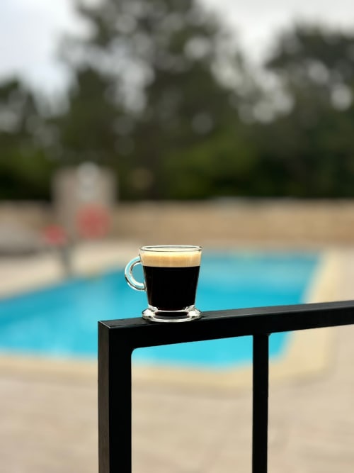 Espresso with crema on poolside table at Quinta Boa Vida cottage, Alcobaça