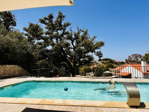 Turquoise pool at Quinta Boa Vida cottage in Alcobaça with ancient olive tree and Mediterranean garden views under clear sky
