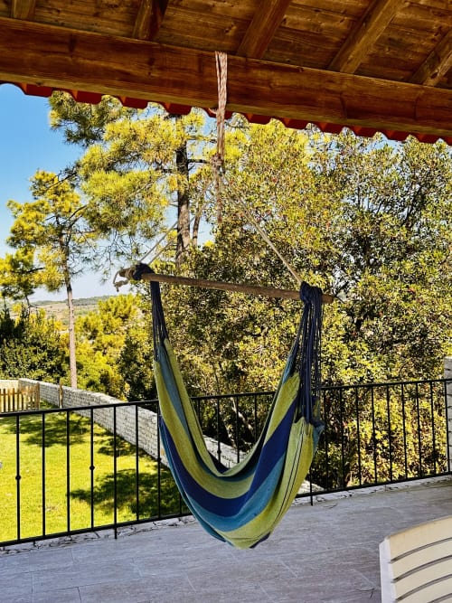 Blue and green hammock on wooden pergola overlooking trees at Quinta Boa Vida cottage, Alcobaça