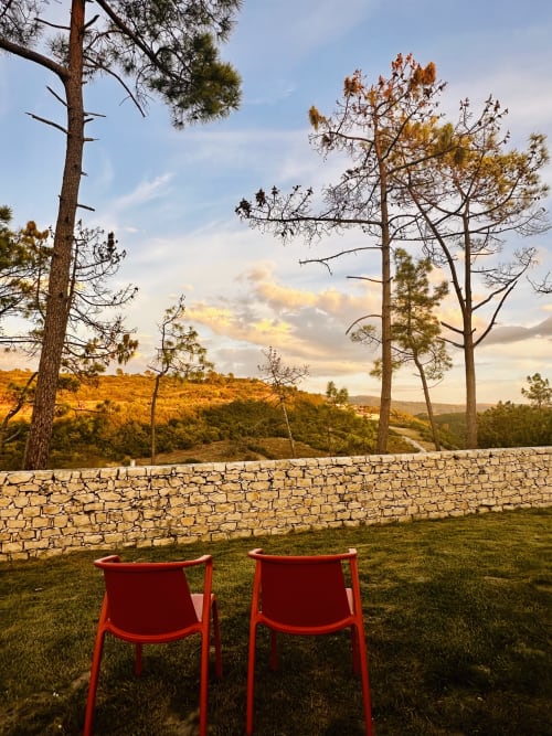Two red chairs overlooking rolling hills and pine trees at Quinta Boa Vida cottage in Alcobaça, Portugal