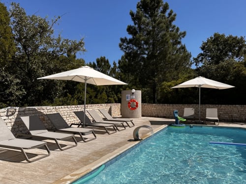 Quinta Boa Vida pool area in Alcobaça with loungers, white umbrellas, and stone walls under blue sky