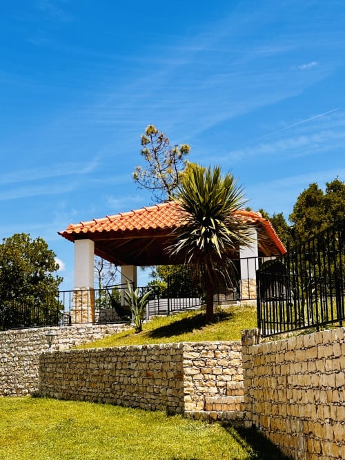 Quinta Boa Vida cottage in Alcobaça with terracotta roof, stone walls, and lush garden under blue sky