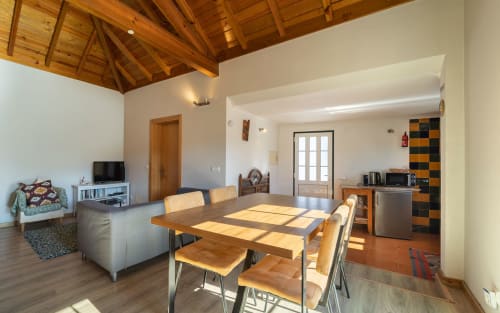 Spacious open-plan living area with wooden ceiling, dining table, kitchenette, and lounge in Orchard View Villa at Quinta Boa