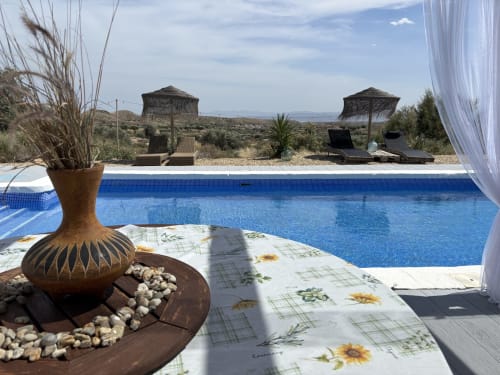 Terraço à beira da piscina de El Sueño de Andalucia com piscina azul, espreguiçadeiras, cerâmica decorativa e estilo andaluz
