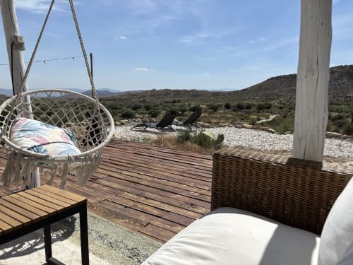 Silla colgante y zona de descanso en terraza de madera con vistas al paisaje desértico de El Sueño de Andalucia, Huércal-Overa