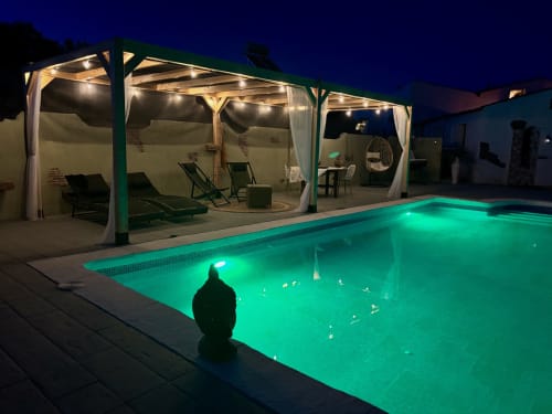 Casa da piscina iluminada em El Sueño de Andalucia com piscina turquesa, espreguiçadeiras e pérgula ao entardecer