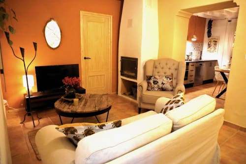 Aconchegante sala de estar rústica da casa rural El Sueño de Andalucía em Huércal-Overa com sofá creme, lareira e vista para as montanhas
