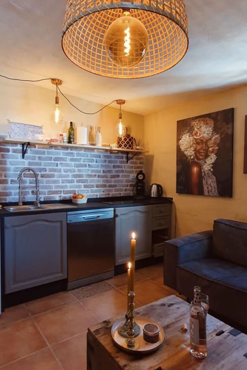Cozinha aconchegante da casa rural El Sueño de Andalucia com bancadas pretas, painel de tijolos e luminárias pendentes