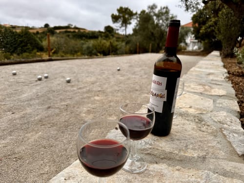 Red wine glasses and bottle at Quinta Boa Vida cottage in Alcobaça, Portugal with bocce ball court view
