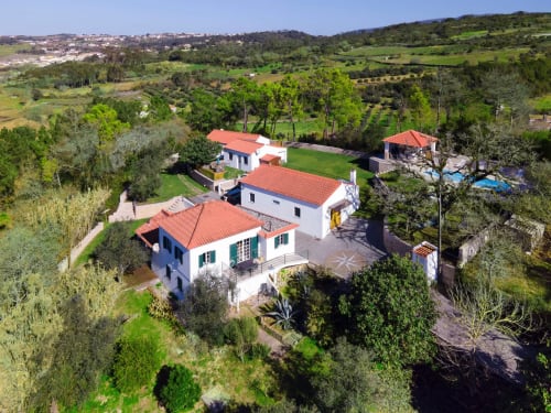 Aerial view of Quinta Boa Vida cottage in Alcobaça with red-tiled roof, gardens, and pool area surrounded by trees