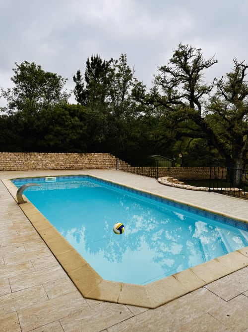Bright blue swimming pool at Quinta Boa Vida cottage in Alcobaça, surrounded by stone patio and mature trees