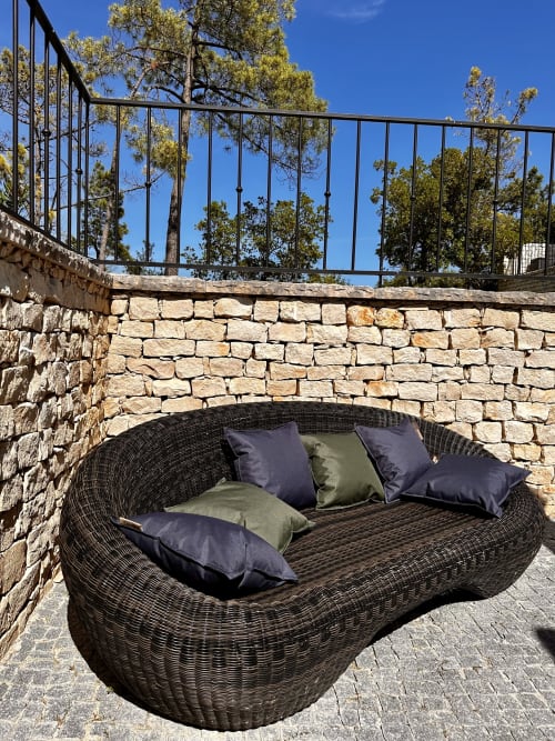 Woven lounge chair with navy and sage pillows on stone patio at Quinta Boa Vida, Alcobaça Portugal