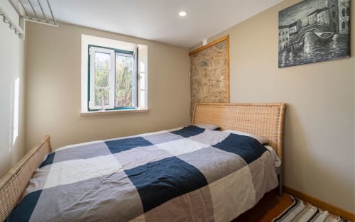 Cozy bedroom at Quinta Boa Vida with wicker bed, striped bedding, garden view window, and nautical artwork in Alcobaça