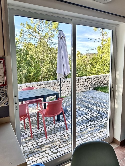 Patio view from Mountain View Chalet at Quinta Boa Vida showing red chairs, table, umbrella, and forested hillside in