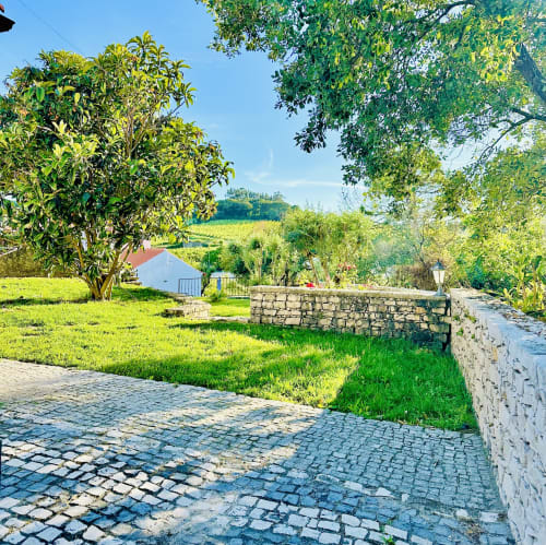 Stone patio and lush garden at Quinta Boa Vida mountain view chalet in Alcobaça, Portugal, with rolling countryside views