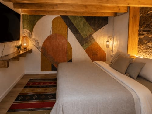 Acogedora habitación en la casa rural Holibai en Baiona con vigas de madera, arte mural abstracto y cama confortable con almohadas grises