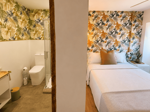 Dormitorio de cabaña en Holibai, Baiona con camas gemelas, cabecero de patrón tropical, baño privado con inodoro moderno y