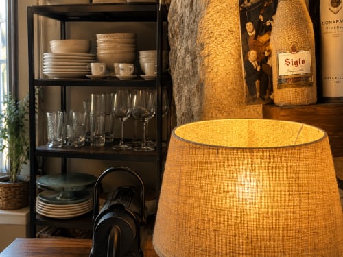 Cottage Holibai en Baiona con elegante comedor, lámpara tejida, botellas de vino y estantería con vajilla