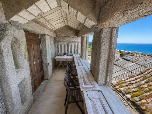 Terraza de piedra rústica en la casa rural Holibai de Baiona con vistas al mar, bancos de madera y arquitectura tradicional