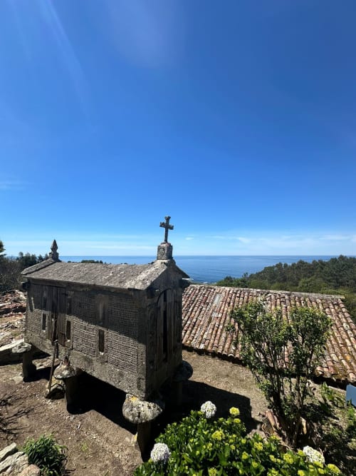 Capilla de piedra histórica con cruz con vistas a la costa gallega cerca de Baiona, España, con viñedos y vistas al mar