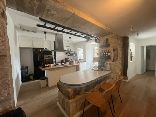 Cocina abierta moderna y zona de comedor en la casa rural Mirada do Roxo en Baiona con detalles en piedra y vistas al mar