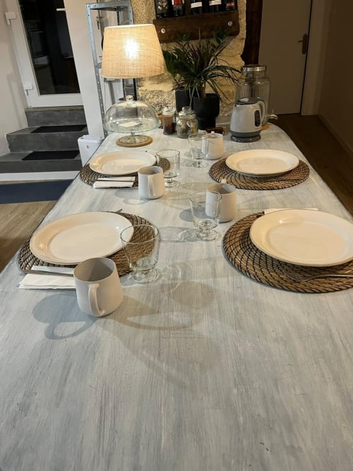 Mesa de comedor elegante para cuatro en la casita Holibai de Baiona con platos blancos, manteleles tejidos y vistas al mar