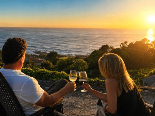 Pareja brindando con vino al atardecer frente al mar en la casita Holibai de Baiona, España