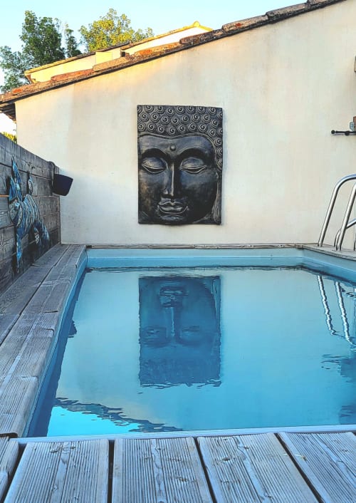 Piscine extérieure avec décoration murale de tête de Bouddha noir à la Suite l'Olive Sacrée Spa en Provence, France