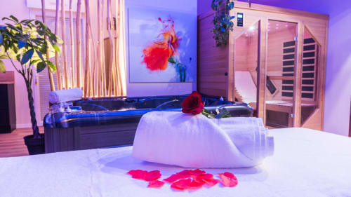 Suite spa luxueuse avec jacuzzi, sauna, éclairage ambiant violet, pétales de roses et équipements wellness modernes en Provence