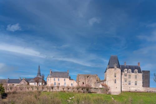 Le Bon Séjour hotel with historic castle ruins in Sainte-Suzanne, France, set in verdant countryside under blue sky