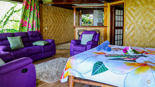 Chambre de villa tropicale avec mobilier violet, linge de lit coloré, murs à motifs et salon avec vue sur mer chez Aimehome