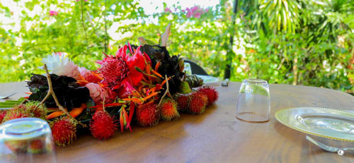 Table tropicale à la villa Aimehome Teavaro avec fruit rambutan, fleurs rouges et vue sur le jardin