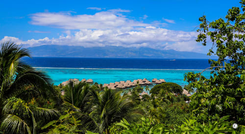 Complexe resort tropical à Teavaro avec bungalows sur l'eau, lagon turquoise et vue sur les montagnes