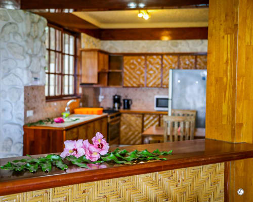 Cuisine chaleureuse en bois avec fleurs roses sur le comptoir, mêlant meubles traditionnels et appareils modernes à la villa Aimehome