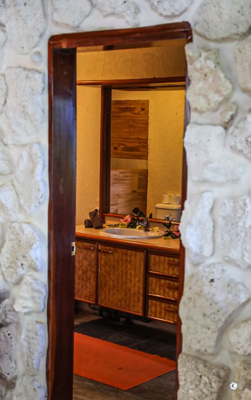Salle de bains avec vasque et miroir à la villa Aimehome Teavaro, aménagée de meubles en bois et murs en pierre