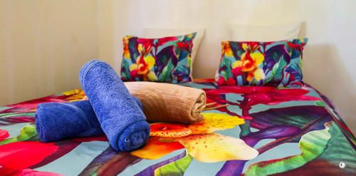 Literie tropicale colorée avec serviettes roulées à la Villa Kia Ora House, Aimehome Teavaro